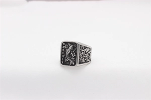 Macro detail of vintage koi fish relief and scrollwork on a silver steel signet ring