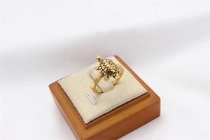 Detailed close-up of a vintage golden sea turtle ring on a beige velvet display stand