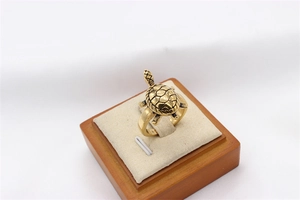 Detail shot of golden turtle ring showing hexagonal shell texture on a wood stand