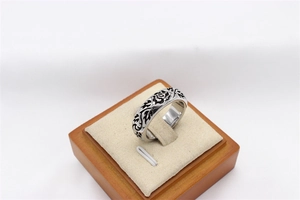Macro shot of vintage silver stainless steel ring with black floral vine engravings
