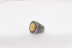 Detail of two-tone steel ring with woven chain texture and hammered gold finish circular top