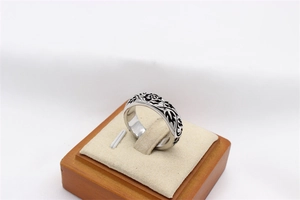 Macro view of vintage silver steel ring with black rose and vine engraving on beige stand