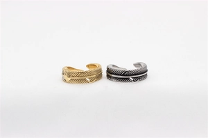 Detailed view of retro gold and silver feather rings with intricate steel texture