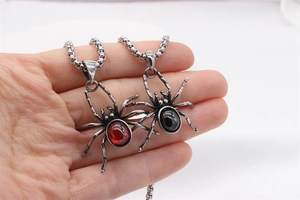 Detail of vintage spider pendant with red and black stones on a steel necklace