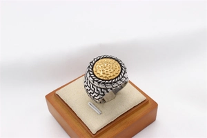 Macro detail of retro men's steel ring with silver woven texture and gold hammered top