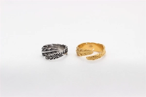 Macro detail of retro feather open rings with intricate textures in silver and gold finish