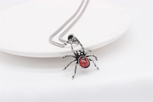 Detailed close-up of retro spider pendant with red gemstone on a stainless steel chain