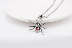 Detail of gothic spider pendant with red gemstone on a stainless steel chain