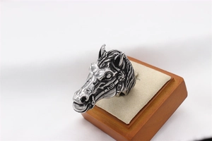 Detailed close-up of retro silver horse head engraving on a vintage steel ring
