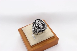 Macro detail of a vintage steel ring with a double-headed eagle emblem on a wooden stand
