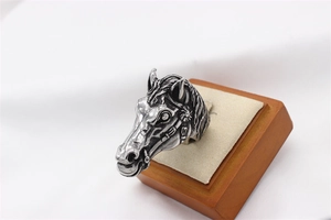 Detailed close-up of a retro white horse head carving on a stainless steel ring band
