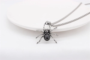 Detailed macro view of vintage spider pendant with black stone on a silver steel box chain