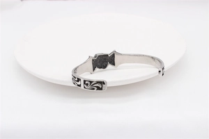 Detail of vintage silver skull bangle with black scroll patterns in punk style