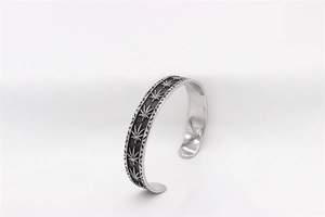 Macro detail of retro maple leaf pattern on vintage steel cuff bracelet for men