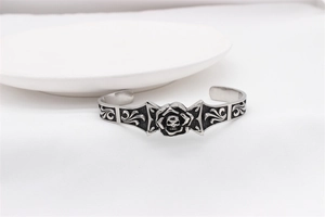 Close-up of vintage gothic skull and rose embossed details on silver steel cuff bracelet