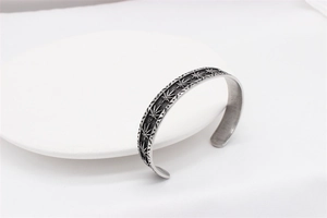Macro detail of vintage maple leaf engraving on a steel cuff bracelet for men