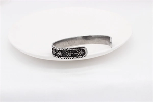 Macro detail of retro maple leaf pattern on vintage steel cuff bracelet for men