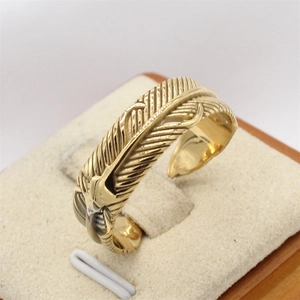 Vintage gold feather steel ring for men featuring detailed bird carvings on white stand