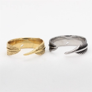 Retro feather-shaped titanium steel rings in gold and silver set on white texture
