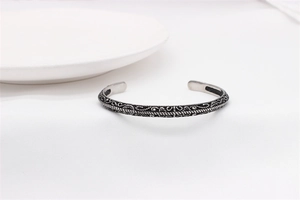 Close-up of vintage steel bangle featuring intricate ethnic floral engraving and oxidized finish