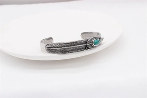 Detailed view of retro feather steel bangle with vintage texture and turquoise stone