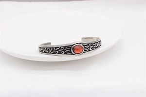 Detail of vintage silver cuff bracelet with red gemstone and intricate floral engravings