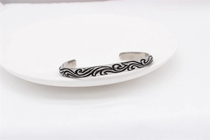 Macro detail of retro men's steel cuff bracelet with vintage black engraved waves