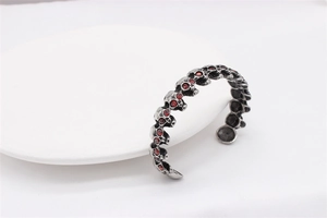 Macro detail of retro skull bracelet with red crystal eyes and vintage silver finish