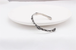 Close-up of vintage crown relief and geometric patterns on a silver steel bangle