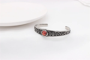 Detail of vintage cuff bracelet featuring ornate floral carvings and a red ruby gemstone