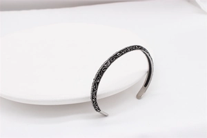 Detail of vintage silver titanium steel cuff bracelet with intricate vine engravings