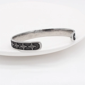 Retro Viking Celtic steel cuff bracelet with black patterns on a white ceramic plate