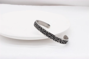 Macro detail of vintage Viking Celtic knot patterns on a silver steel open cuff bracelet