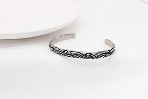 Macro view of retro stainless steel cuff bracelet with intricate black wave patterns