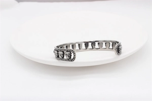 Detailed close-up of retro silver skull cuff bracelet with hollow gothic relief patterns