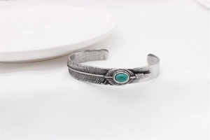 Detail view of retro feather cuff bracelet with turquoise stone in stainless steel