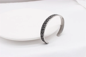 Detailed close-up of retro silver Celtic knot patterns on a stainless steel cuff bracelet