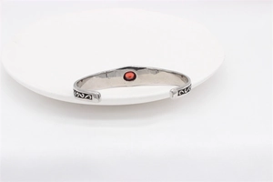 Detail of vintage silver titanium steel cuff featuring red ruby and ornate engraving