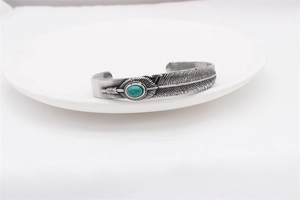 Detailed close-up of a vintage steel feather cuff bracelet with inlaid turquoise stone