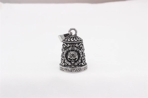 Close-up of retro stainless steel bell pendant featuring a punk skull and scroll engraving