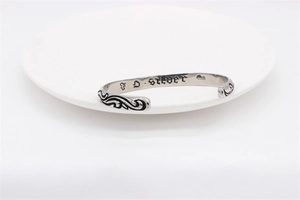 Close-up of vintage steel cuff with floral engraving and gothic inner lettering