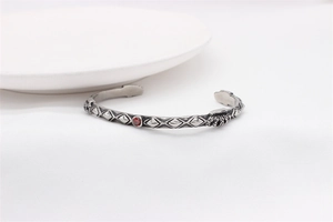 Detail of silver vintage cuff bracelet with red zircon and embossed crown crest
