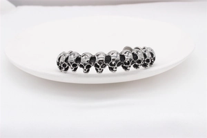 Detailed close-up of a vintage skull cuff bracelet in silver finish on a white ceramic tray