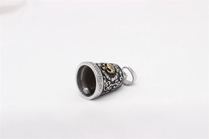 Macro detail of vintage steel bell pendant featuring a gold skull and gothic carvings