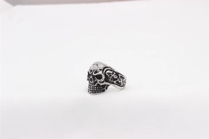 Detailed macro view of vintage silver skull ring with side carvings and punk textures