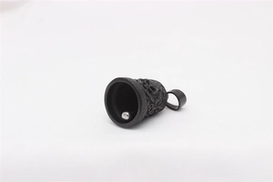 Detailed macro of vintage black bell pendant with intricate dragon relief and silver clapper