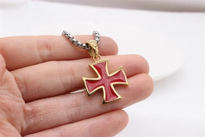 Macro detail of vintage red enamel Maltese cross pendant with gold edge on box chain