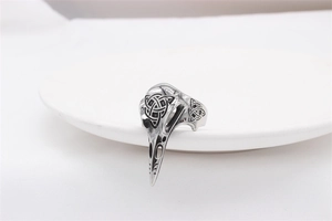 Macro detail of Viking raven skull ring featuring intricate Celtic knots on silver steel