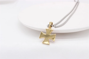 Macro shot of minimalist gold cross pendant on a silver box chain over white porcelain