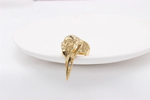 Macro detail of golden gothic bird skull ring featuring intricate Celtic knots